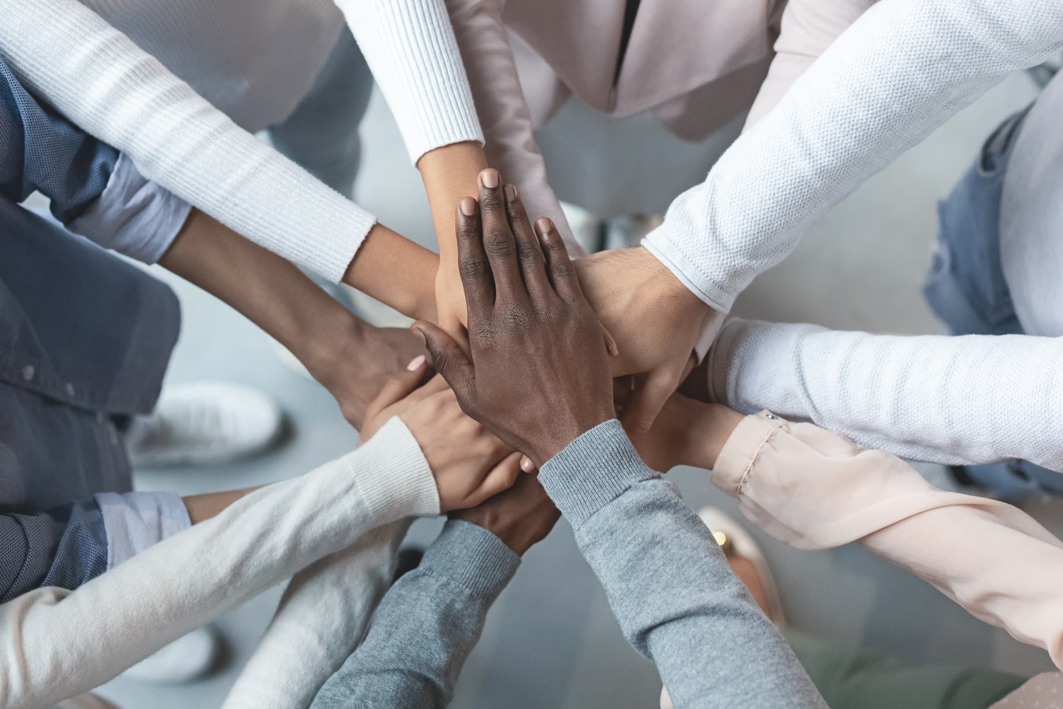 Top view of international business team showing cooperation with putting their hands together on top of each other