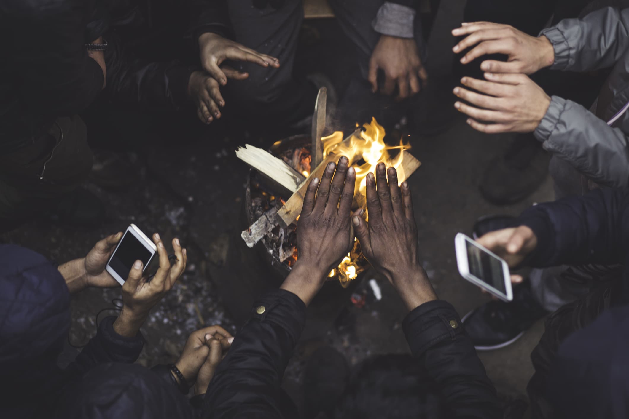 Migrants find shelter from rain and cold weather and warm your hands around the fire.