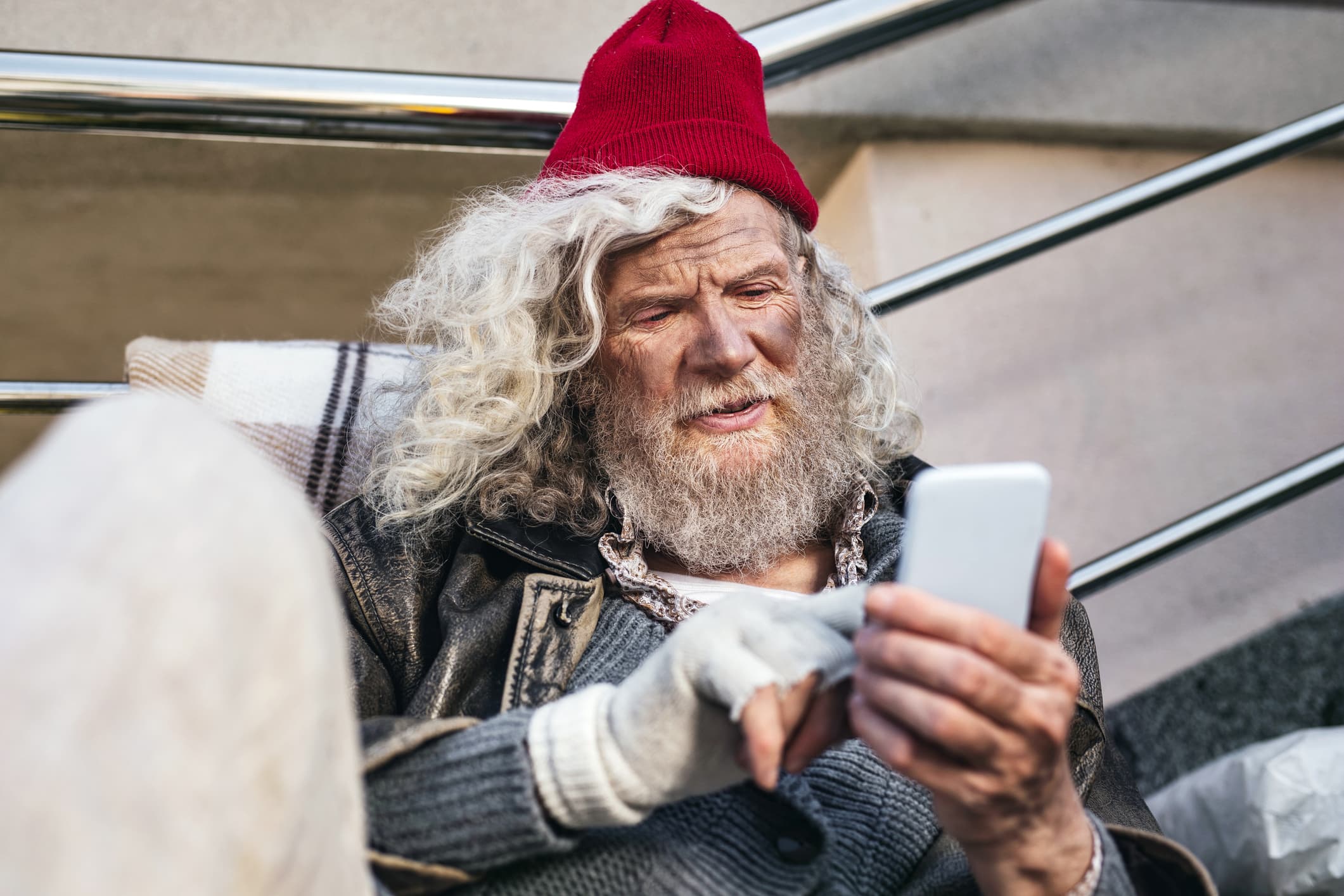 Joyful mood. Positive bearded man smiling while using a smartphone